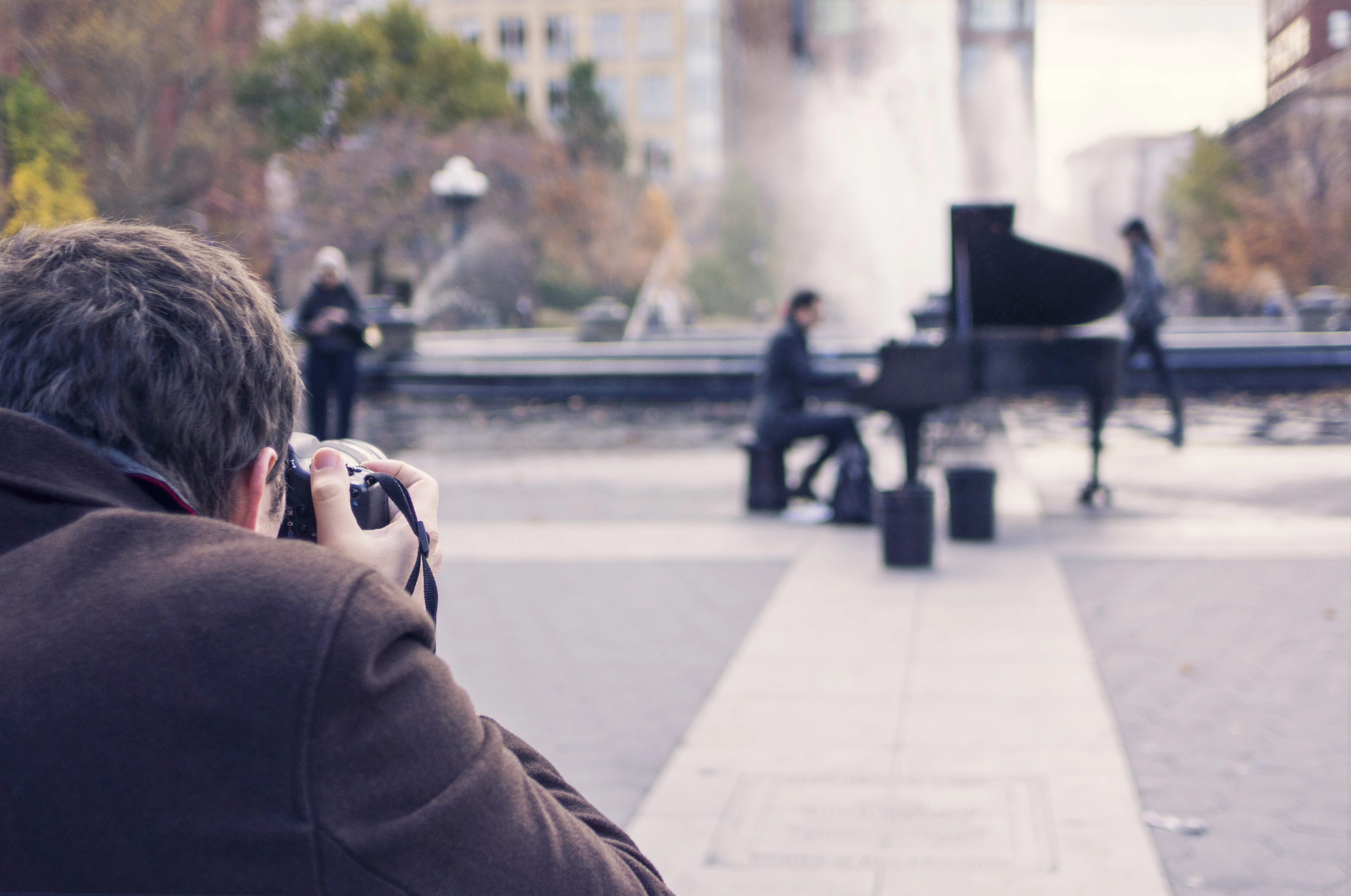 Photographer taking a picture of a pianist playing piano on a street